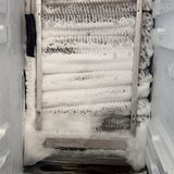 Frost packed solid on a freezer’s evaporator coil, its back panel off